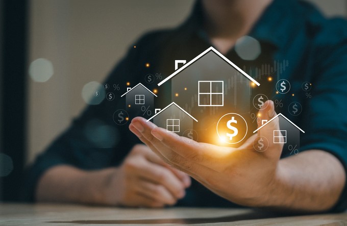 A man holding a virtual image of a house surrounded by floating money symbols, representing financial investment or property value.