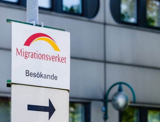 Directional sign with the Migrationsverket logo and arrows pointing the way to the Swedish Migration Agency office