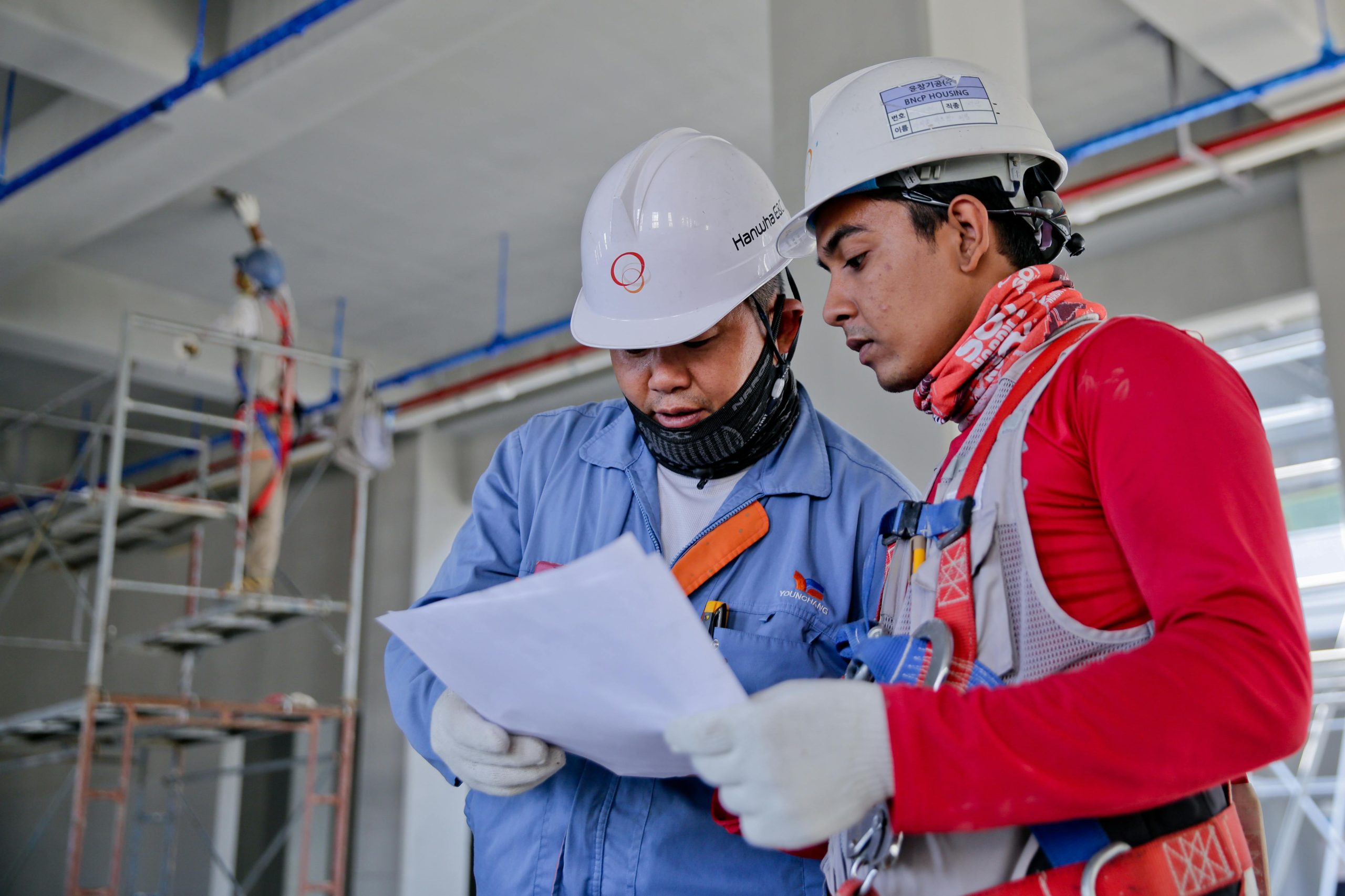 Two construction workers wearing helmets discussing work at a construction site