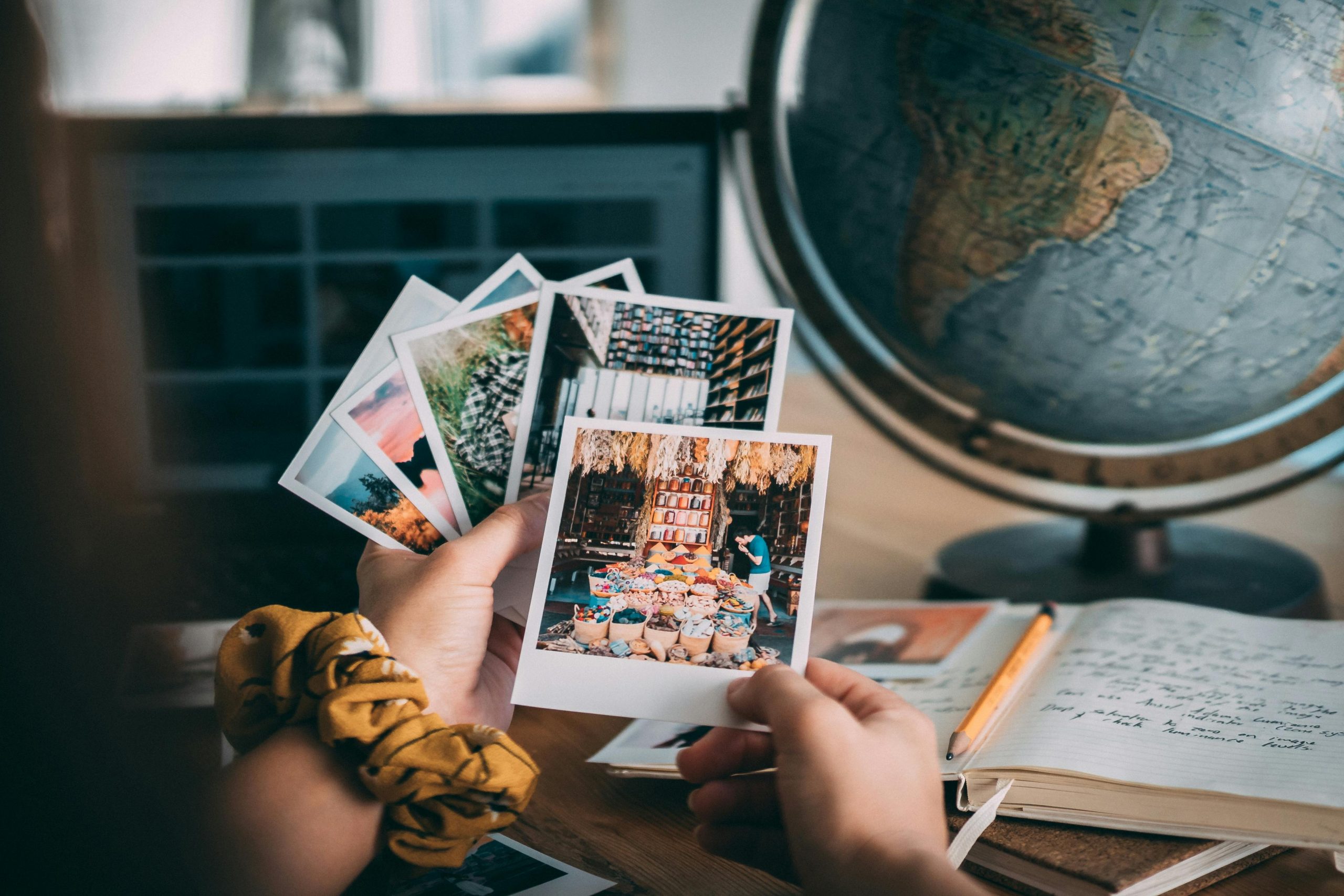 A person sitting and looking at photographs, with a globe visible beside them.